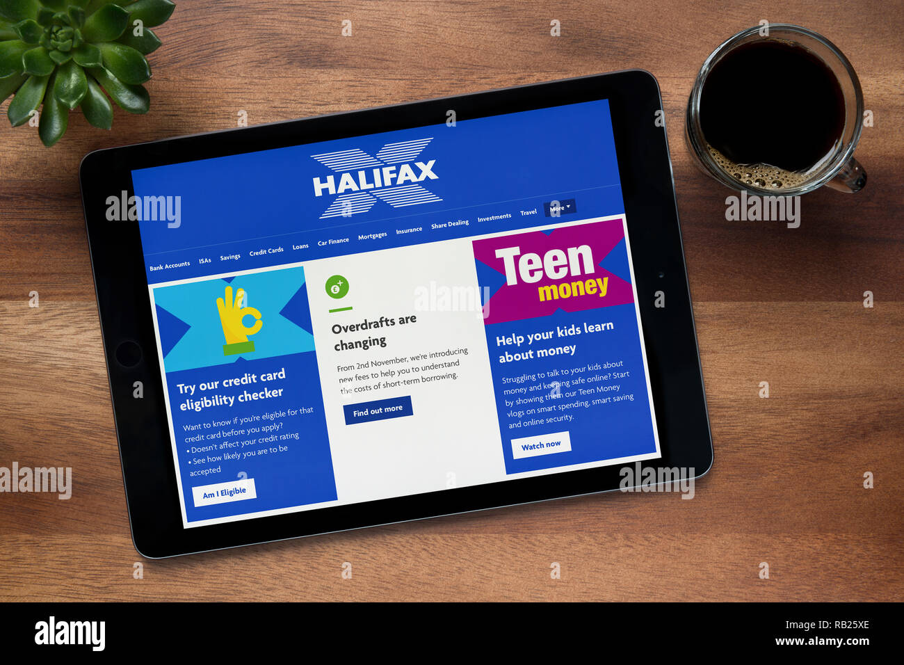Il sito web di Halifax è visto su un tablet iPad, su di un tavolo di legno lungo con un caffè espresso e una pianta di casa (solo uso editoriale). Foto Stock