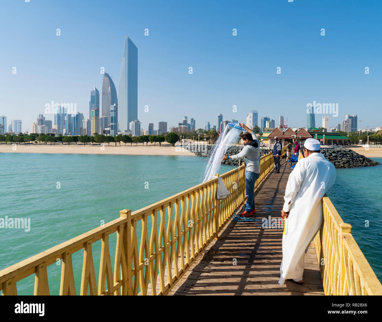 Skyline di moderne torri di uffici in CBD Downtown dal molo pubblico con gli uomini di pesca in Kuwait City in Kuwait Foto Stock