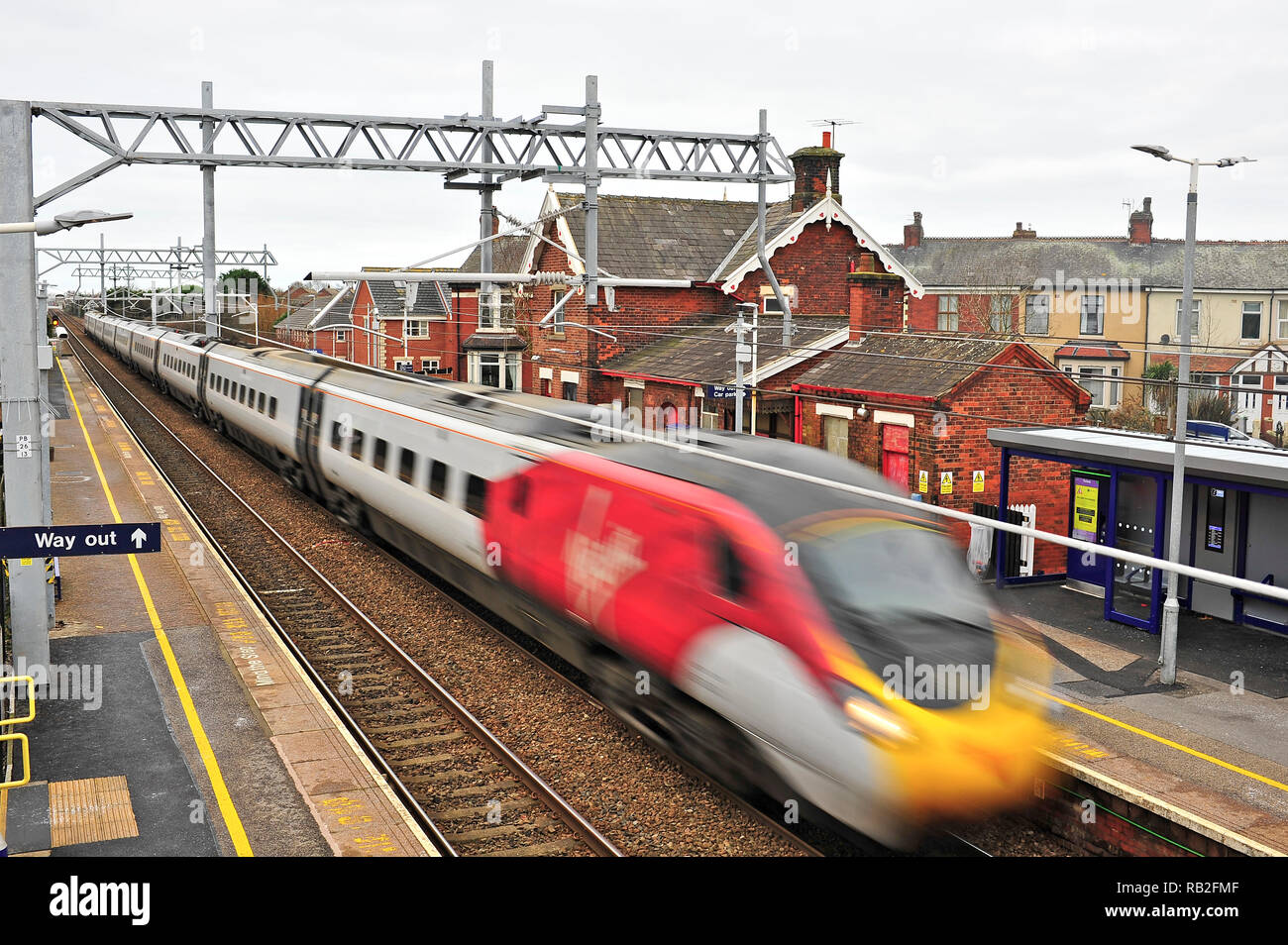 Inter City vergine treno passa attraverso una piccola stazione urbana sulla nuova elettrificata di Blackpool Preston linea sul suo modo di London Euston Foto Stock