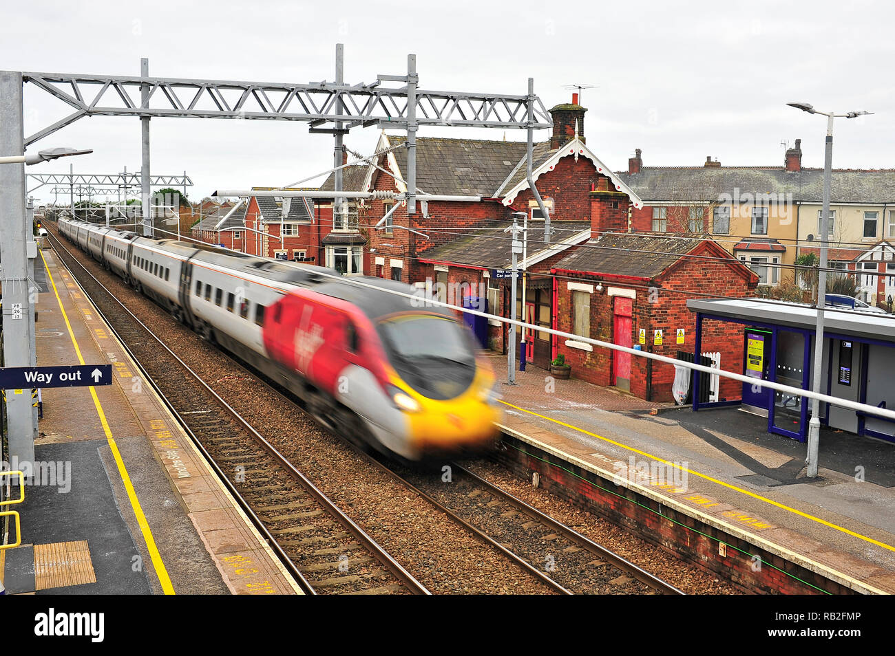 Inter City vergine treno passa attraverso una piccola stazione urbana sulla nuova elettrificata di Blackpool Preston linea sul suo modo di London Euston Foto Stock