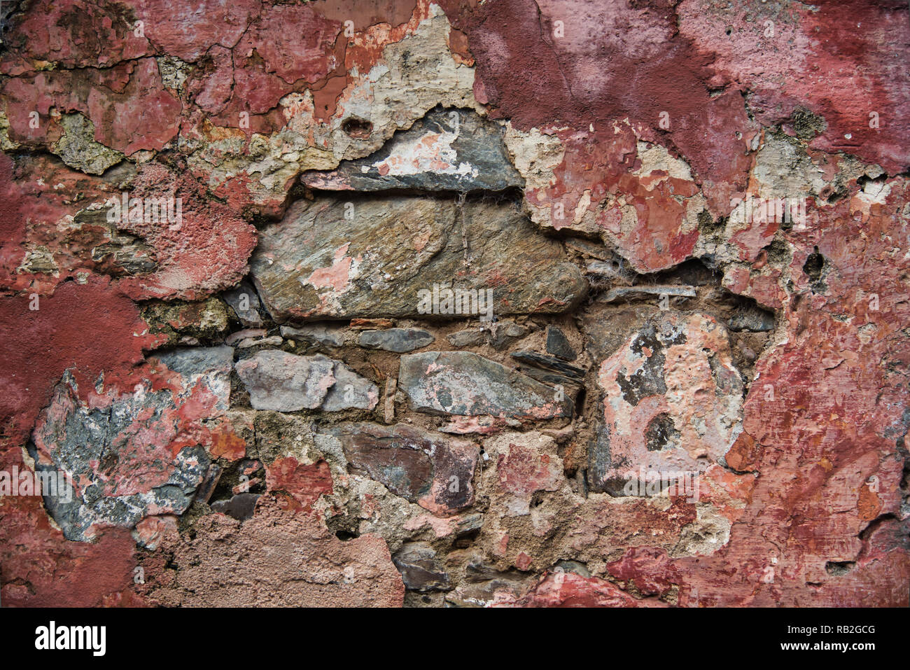 Antico muro di pietra con una texture colorate in rosso i toni non verniciata Foto Stock