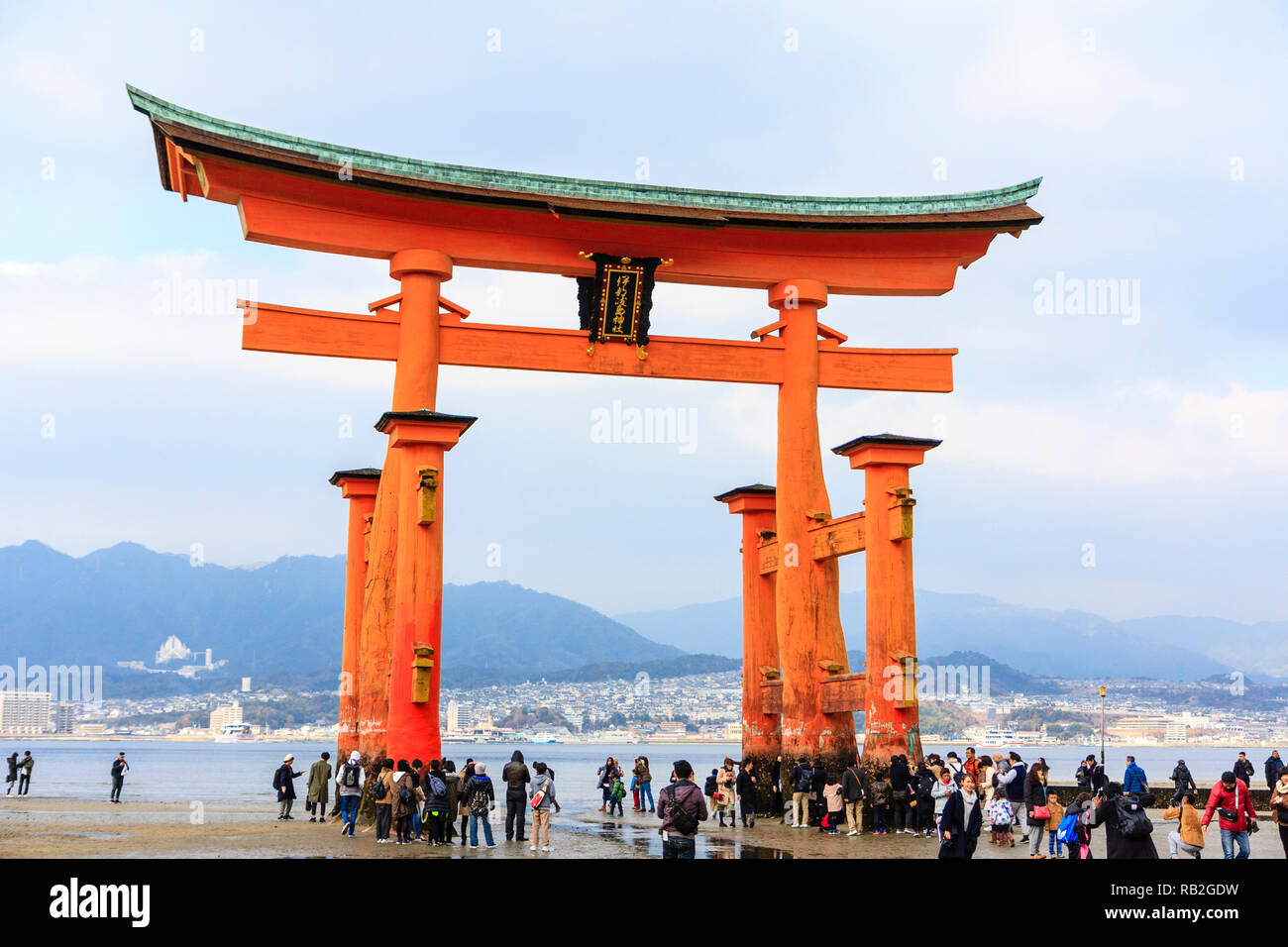 Il Giappone. Il grande Torii presso il Santuario scintoista di Itsukushima sull'isola di Miyajima a bassa marea con la folla di persone intorno a base di sei pilastri. Foto Stock