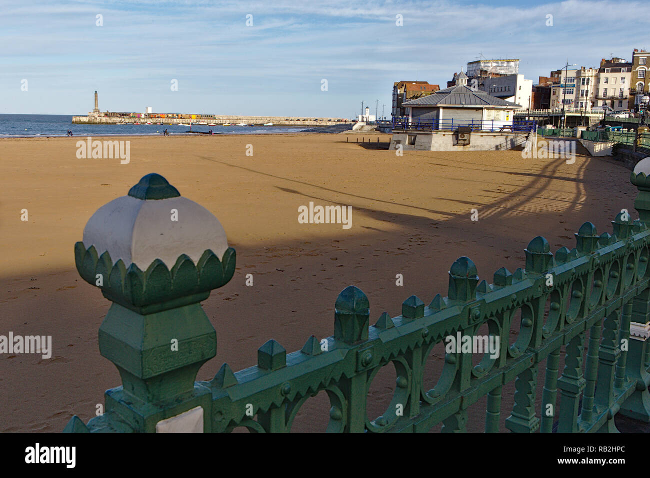 Vista dal recinto verde attraverso il giallo sabbia di Margate Beach in una giornata di sole con ombre lunghe Foto Stock