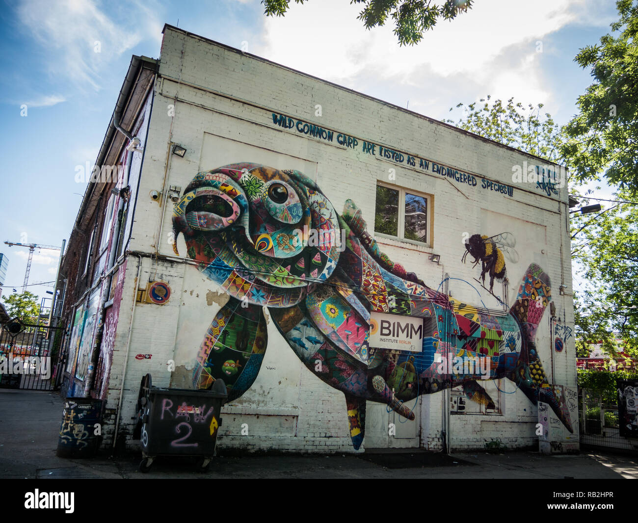 Berlino, Germania - 21 Maggio 2018: vecchi edifici industriali decorata con pesci colorati e bee graffiti, arti di strada Foto Stock