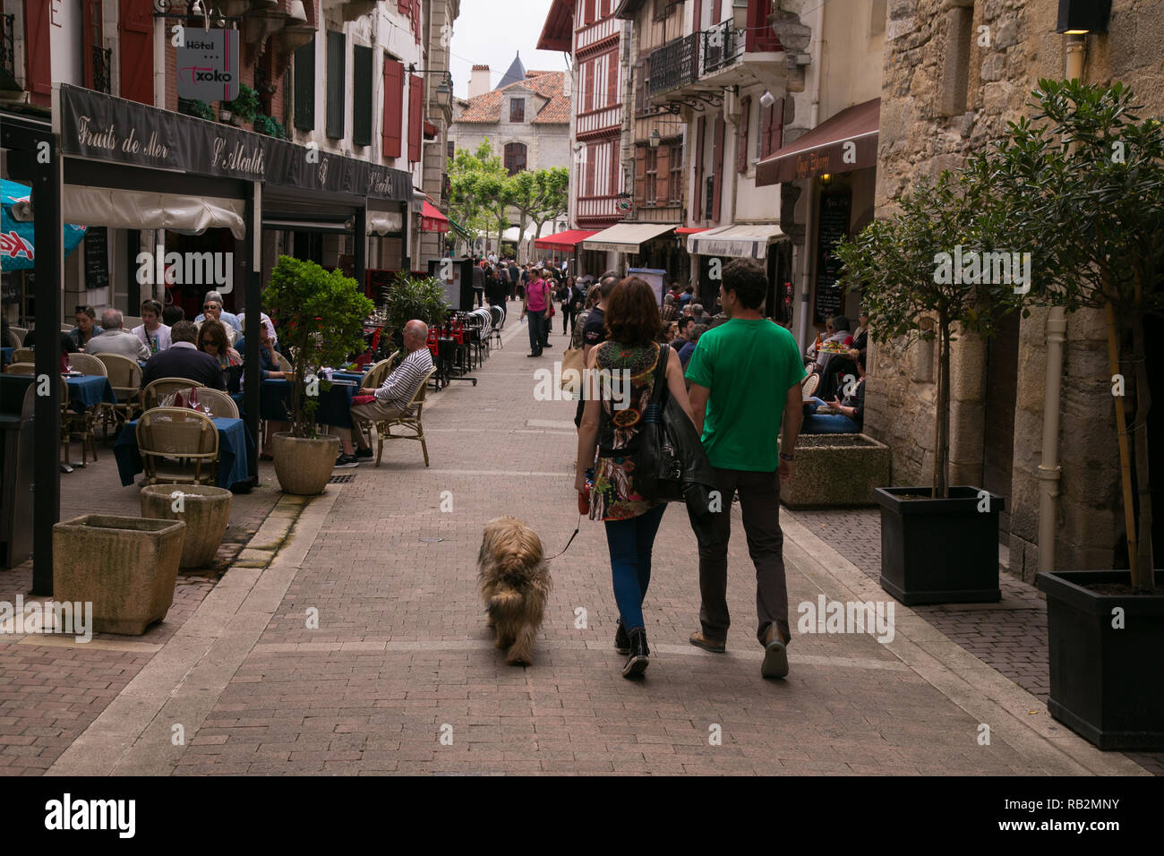 Un giovane a piedi il loro cane giù un pedone friendly street in St Jean de Luz, Francia. Foto Stock