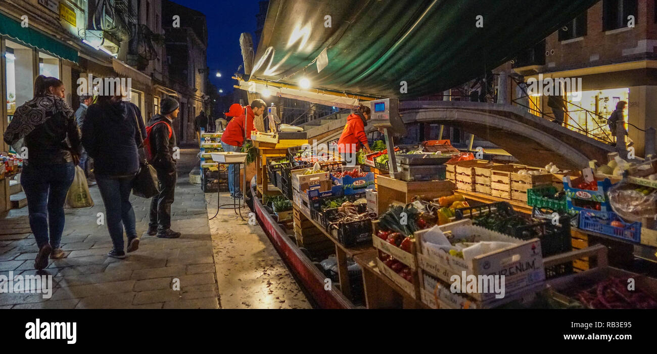 Barca di verdure, mercato al crepuscolo, bancarella di prodotti freschi in un canale accanto a un ponte, vita locale autentica, Cannaregio, Venezia, Italia. Foto Stock