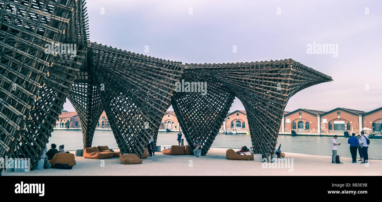 Pavillon in legno intrecciati della Biennale d'architettura all'Arsenale, Venezia, Italia, davanti a sale storiche in mattoni sull'acqua Foto Stock