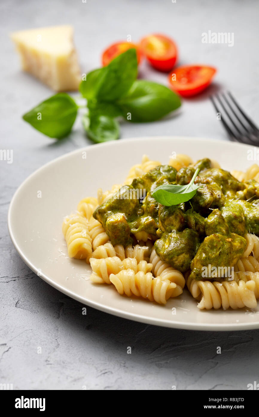Pasta con carne di pollo e salsa di basilico su un cemento grigio sfondo Foto Stock