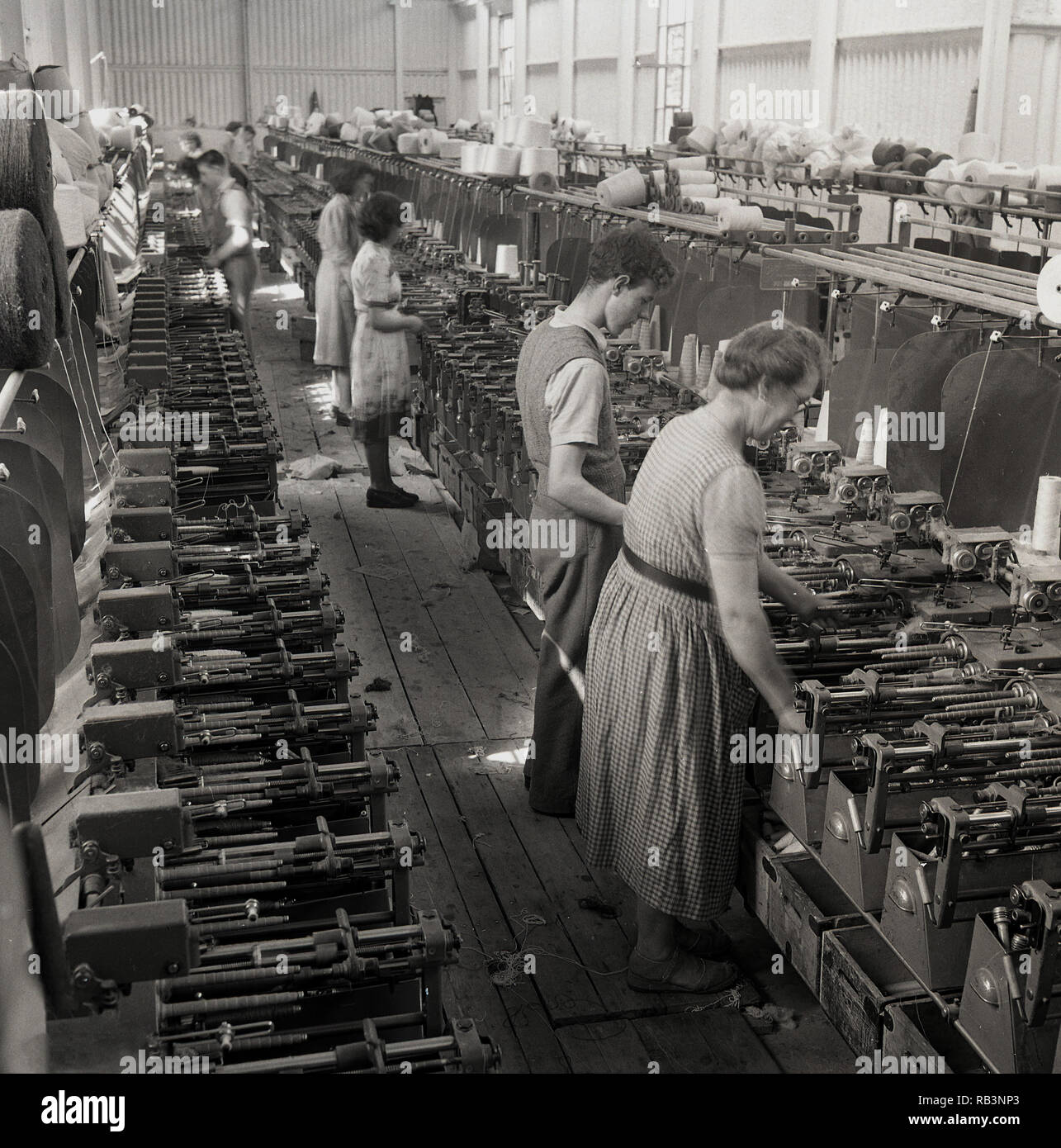 Degli anni Cinquanta, mulino tessile o in fabbrica, i lavoratori sulla linea di produzione mediante tessitura meccanica telai, Irlanda del Nord. In questa epoca, il settore tessile è stato un importante datore di lavoro e quasi tutti i villaggi e città in Irlanda del Nord aveva un mulino o la fabbrica coinvolti nell'industria. Foto Stock
