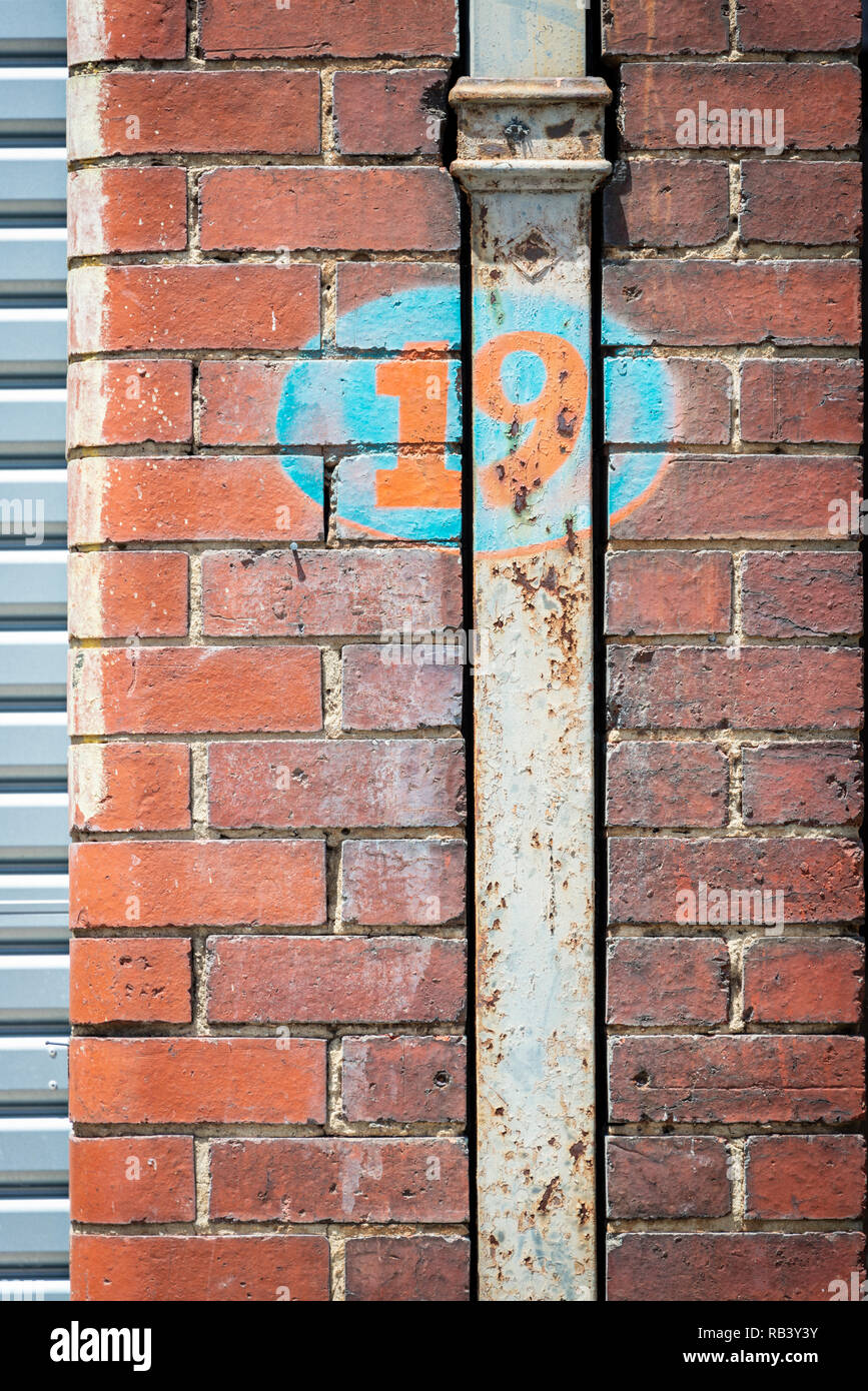 Vecchio numero retrò 19 segno, dipinta su mattone e tubo verso il basso Foto Stock