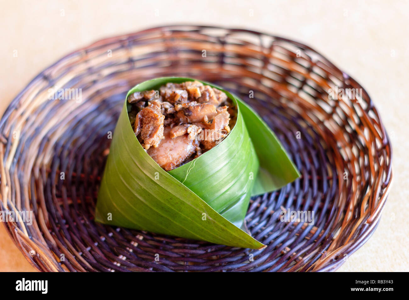 Un cibo salato di riso al vapore condito con carne e avvolti in foglie di banano Foto Stock