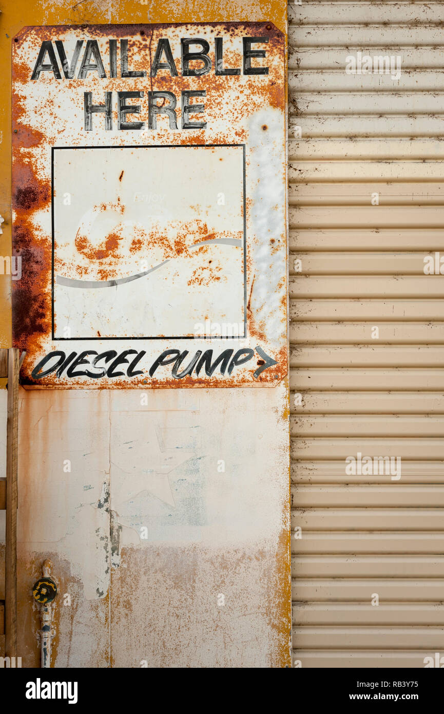 Un vecchio Coke, disponibile qui / pompa diesel segno sul lato di un abbandono della stazione di gas Foto Stock