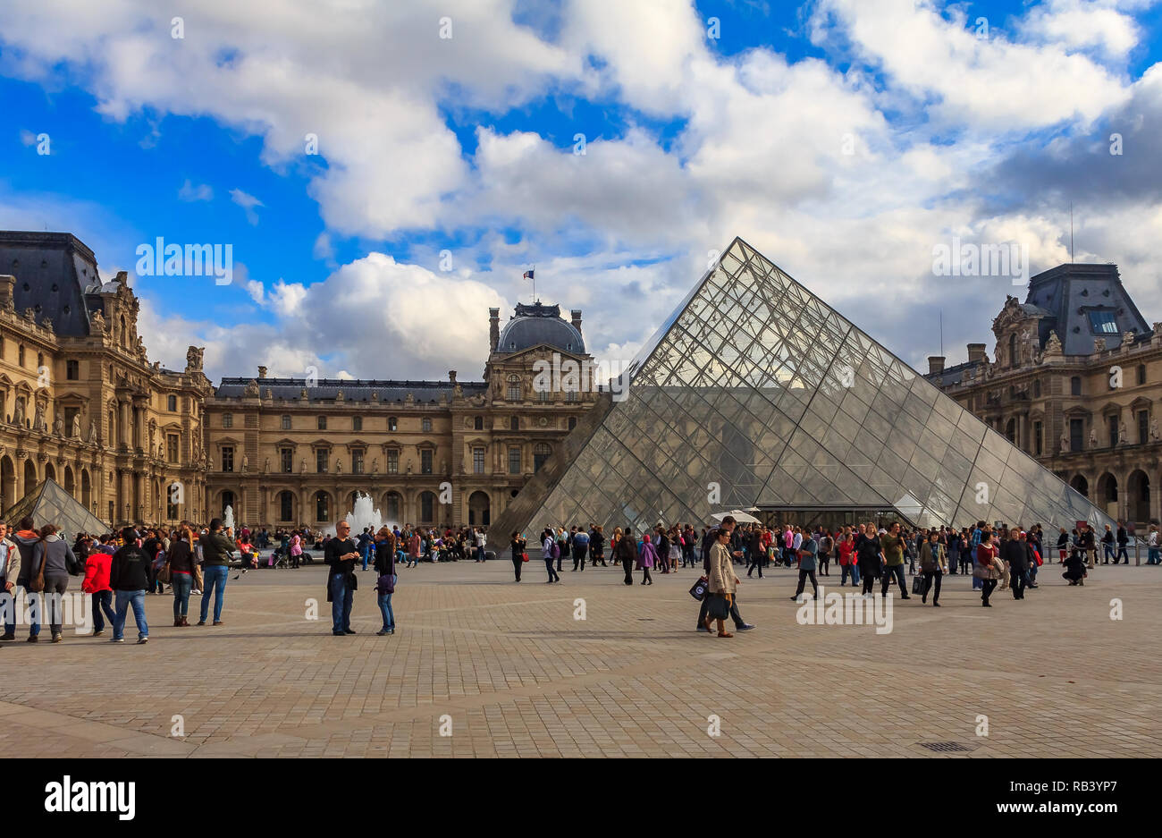 Parigi, Francia - 25 ottobre 2013: Turisti che camminano di fronte alla famosa Piramide e al Museo del Louvre, uno dei più grandi musei d'arte del mondo Foto Stock