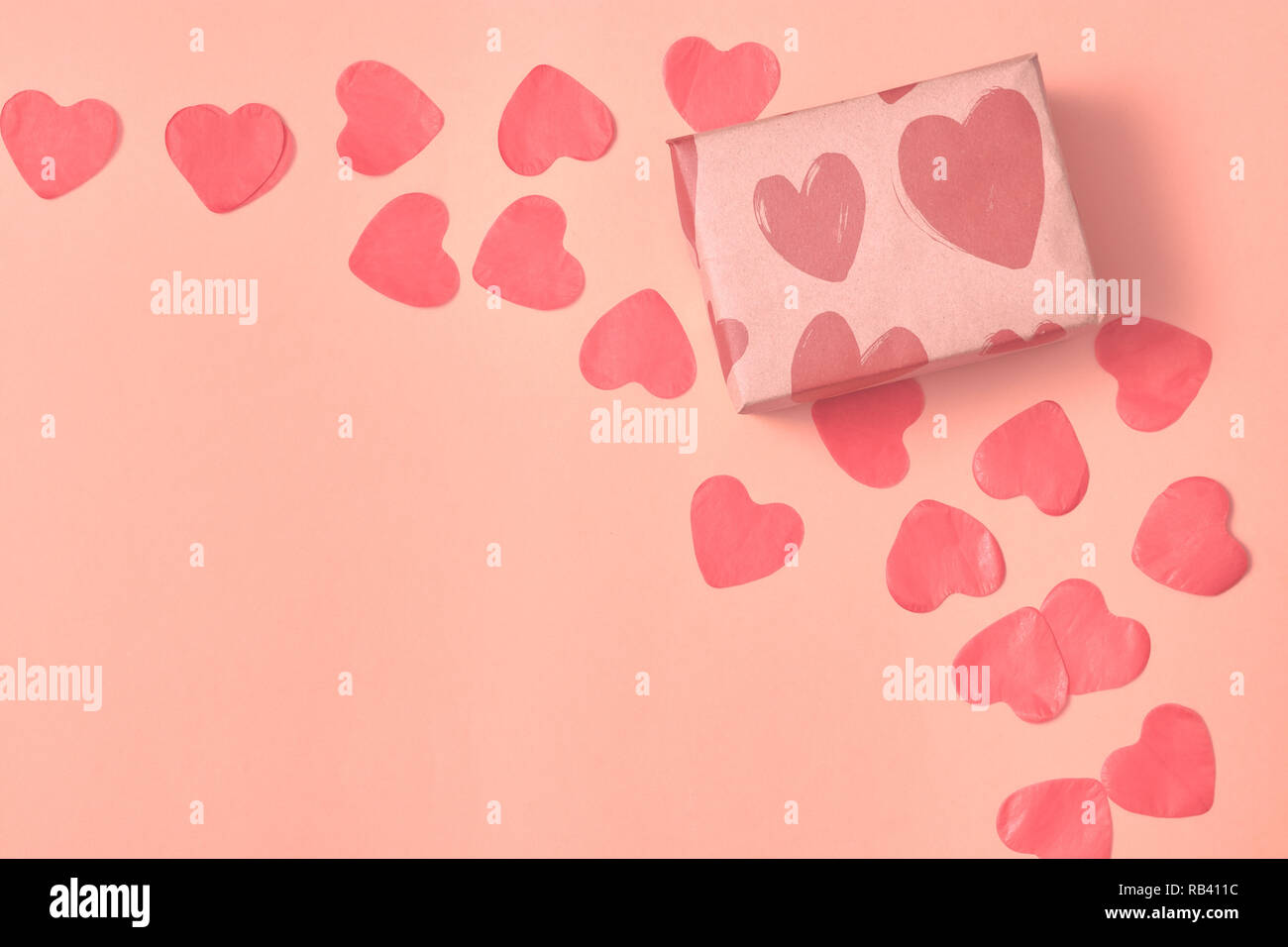 Regalo in carta Kraft con cuori rossi su sfondo rosa con cuori. Il concetto di San Valentino. vista da sopra . copia dello spazio. Foto Stock