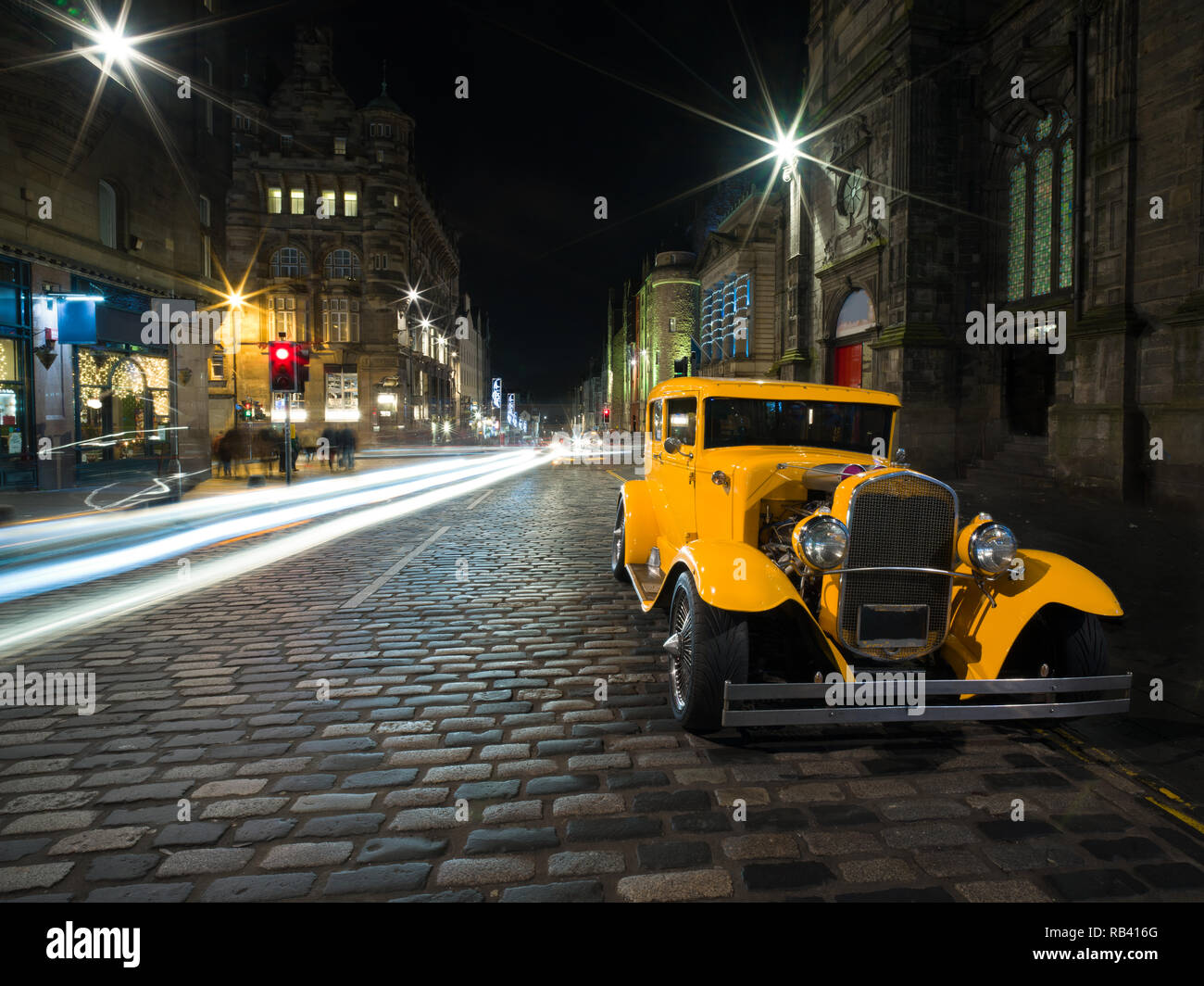 Bella e antica giallo auto sulla strada di ciottoli di notte nel borgo medievale di Edimburgo Foto Stock