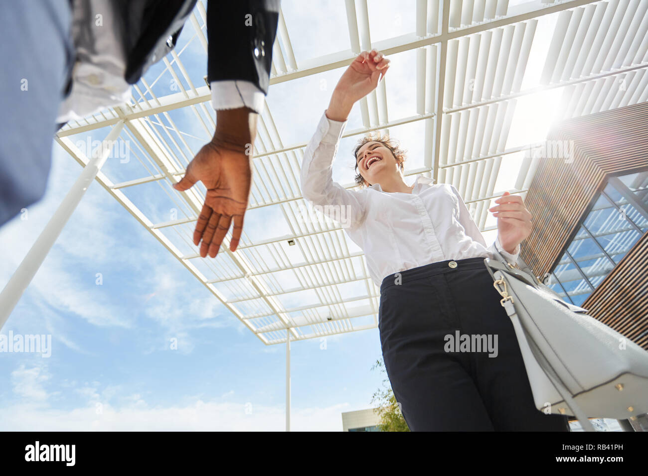 Due persone di affari allietare circa il successo e rendono alta cinque di fronte all'ufficio Foto Stock