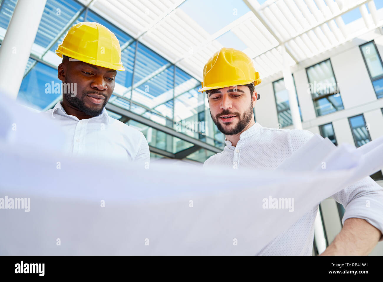 Due architetti o ingegneri presso la costruzione pianificazione con un disegno di costruzione Foto Stock