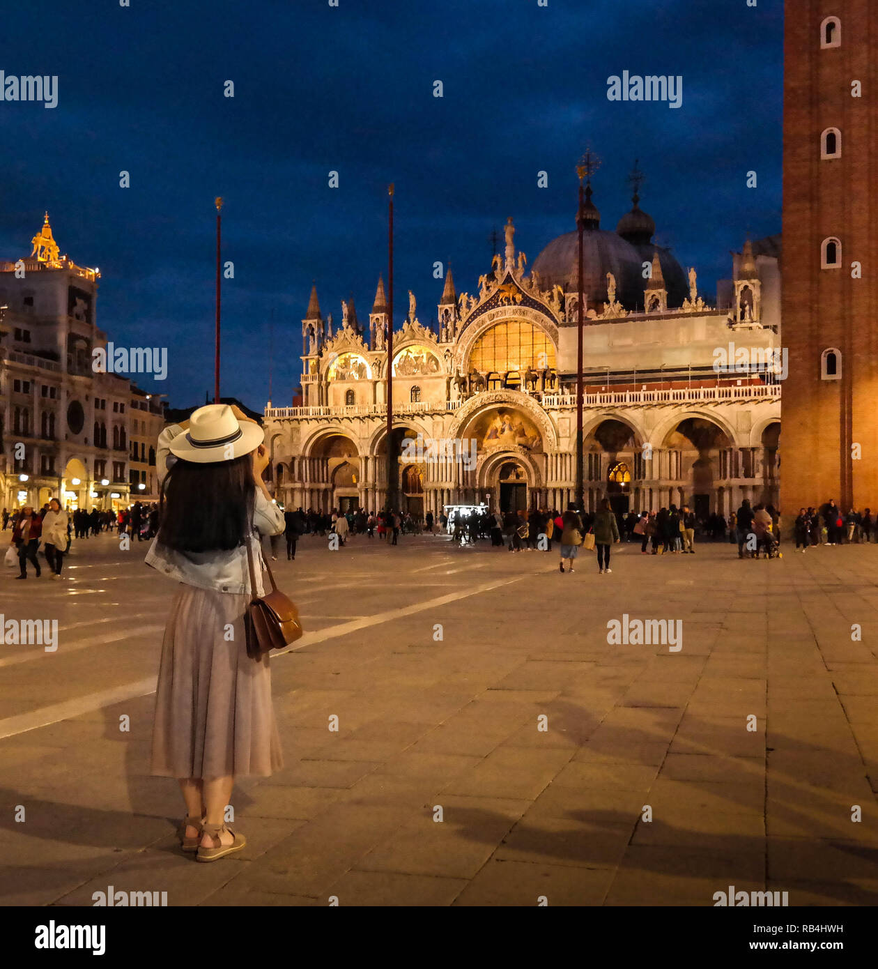 Il turista fotografa la Basilica di San Marco di notte in Piazza San Marco, Venezia, Italia, con un'architettura illuminata e un cielo notturno blu profondo. Foto Stock