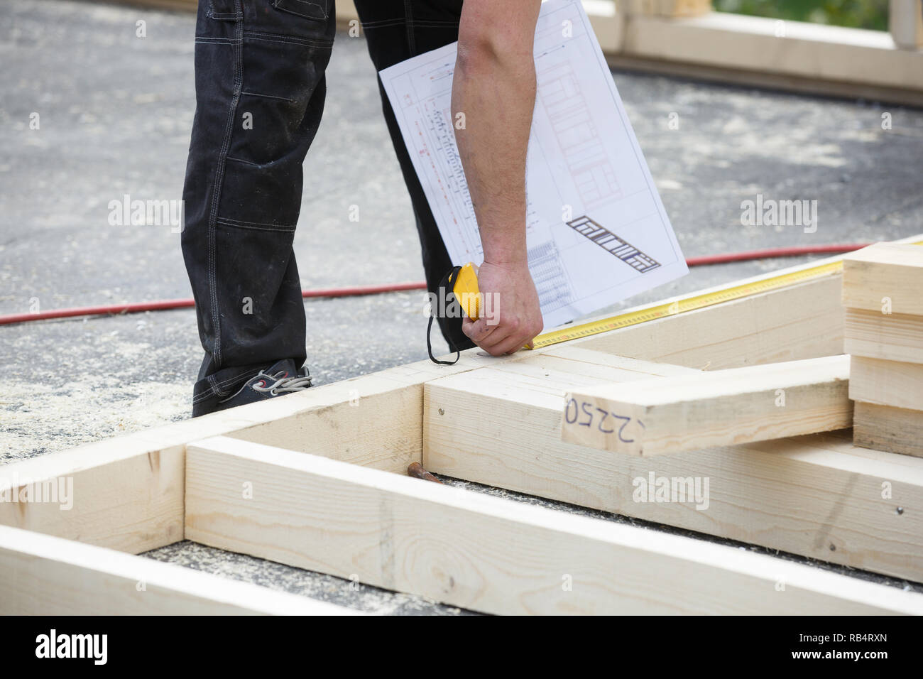 Falegname in legno di misura 2x4' struttura a parete, controllo del piano di costruzione al cantiere. Edilizia, carpenteria concetto. Foto Stock