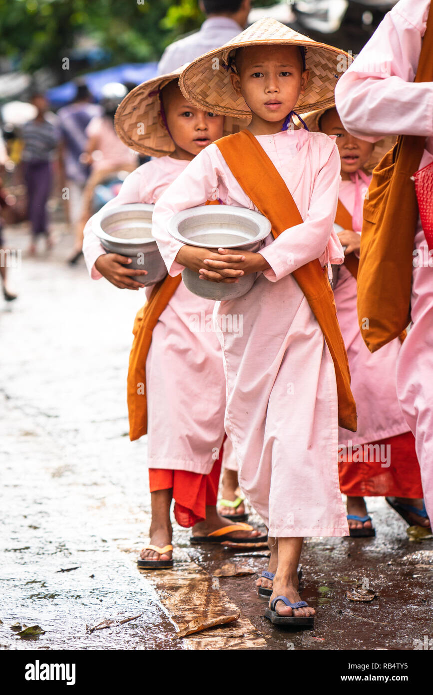 Coda di bambini monaci nel mercato con theri bocce e i loro cappelli, mandalay myanmar Foto Stock