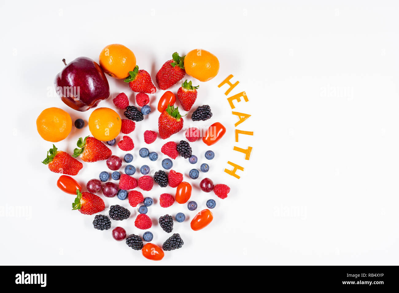 A forma di cuore la disposizione di frutta con la parola la salute fatta di bucce di mandarino in un pulito lo sfondo bianco con copia spazio. Foto Stock