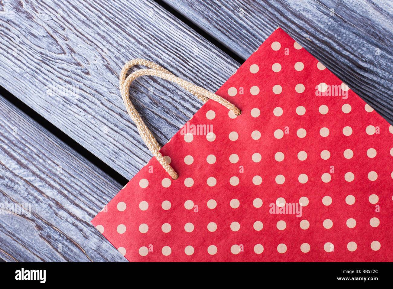 Red shopping bag su tavole di legno. Rosso a pois dono carta borsa su grigio Sfondo di legno. Foto Stock