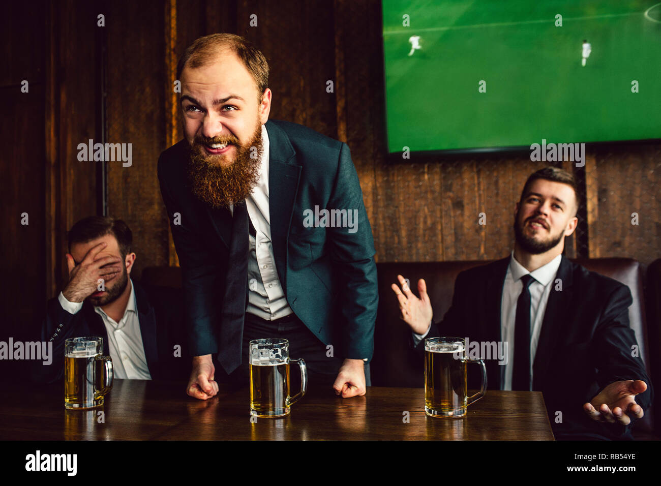 Giovane uomo nel mezzo di alzarsi e di sporgersi in avanti. Egli è felice. Altri due uomini sono sconvolti e infelice. Ragazzo sulla sinistra tenere la mano sul viso. Foto Stock