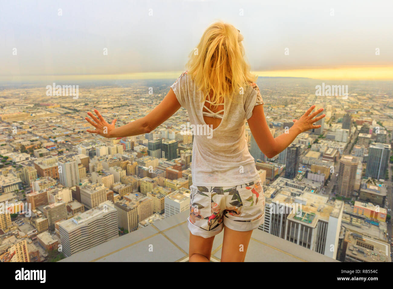 Vista aerea di Los Angeles skyline in California, Stati Uniti. Viaggi e turismo concetto americano. Bionda donna turistica cercando presso il Centro Cittadino di LA cityscape dalla piattaforma di osservazione. Sunset shot. Foto Stock