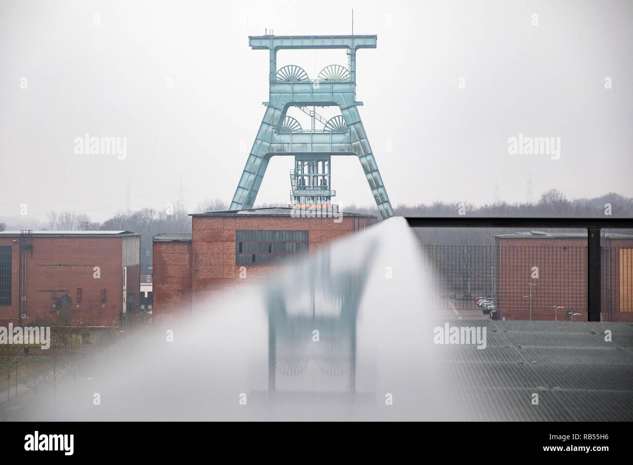 Der Förderturm der Zeche Ewald spiegelt sich in einem Geländer. Foto Stock