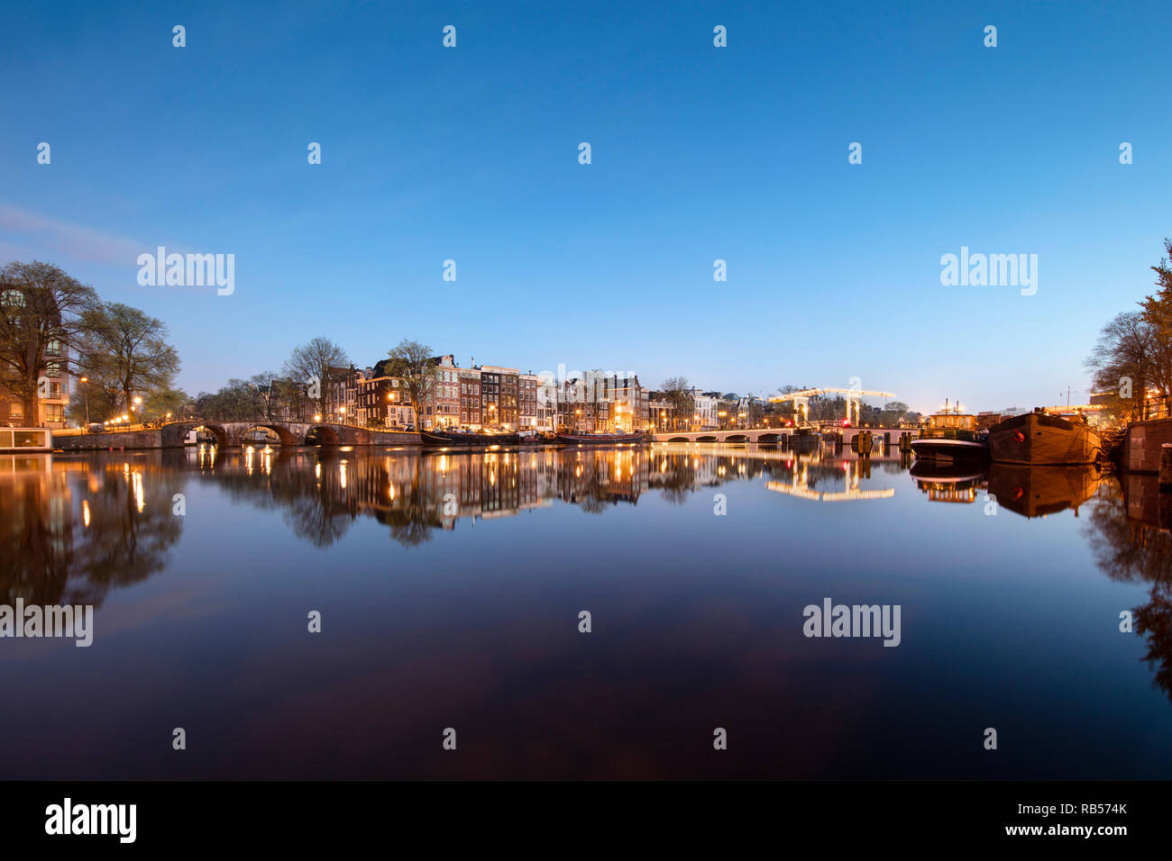 I Paesi Bassi, Amsterdam, Canal case e case galleggianti lungo il fiume Amstel. A destra del ponte Magro. All'alba. Foto Stock