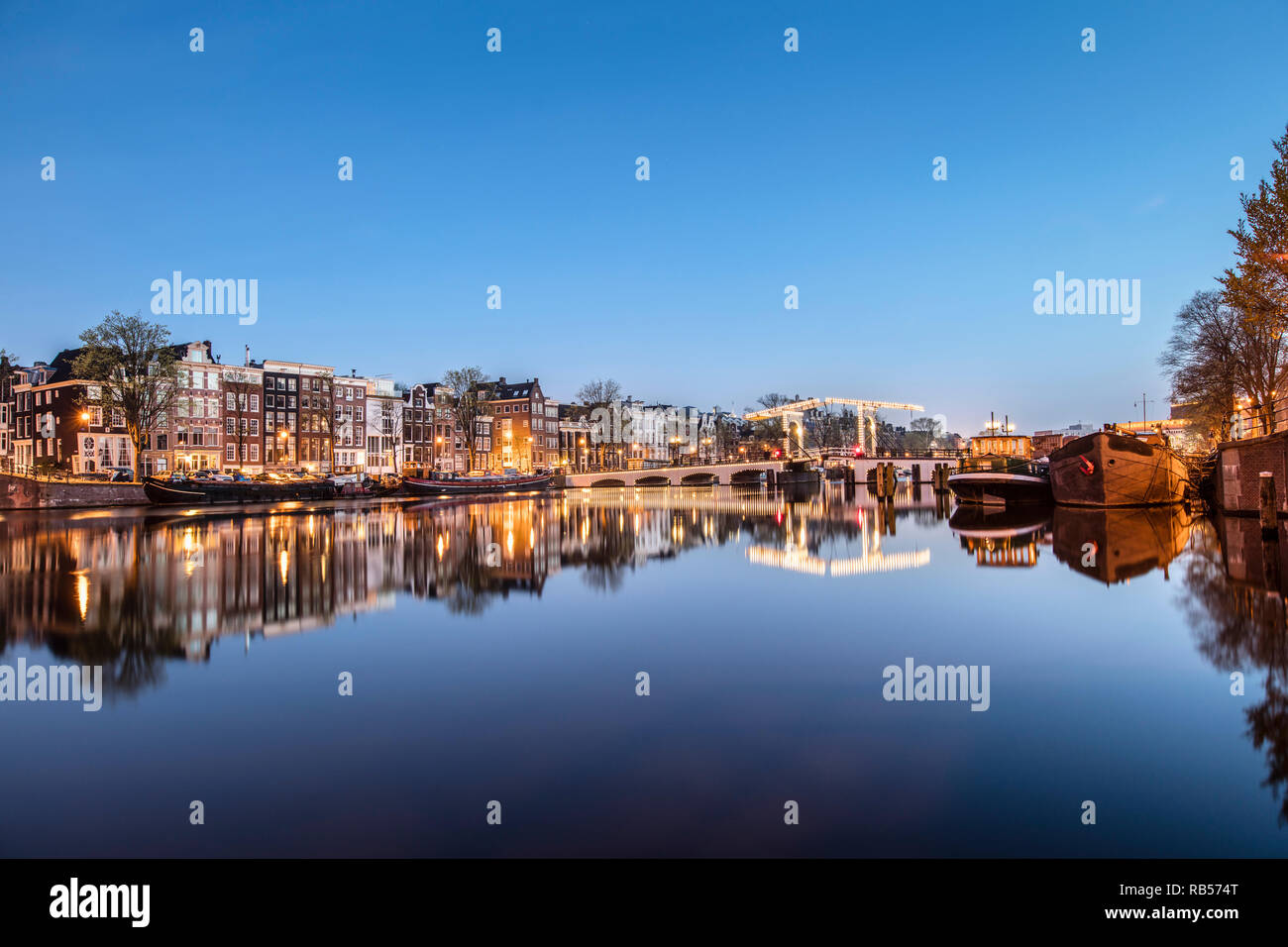 I Paesi Bassi, Amsterdam, Canal case e case galleggianti lungo il fiume Amstel. A destra del ponte Magro. All'alba. Foto Stock