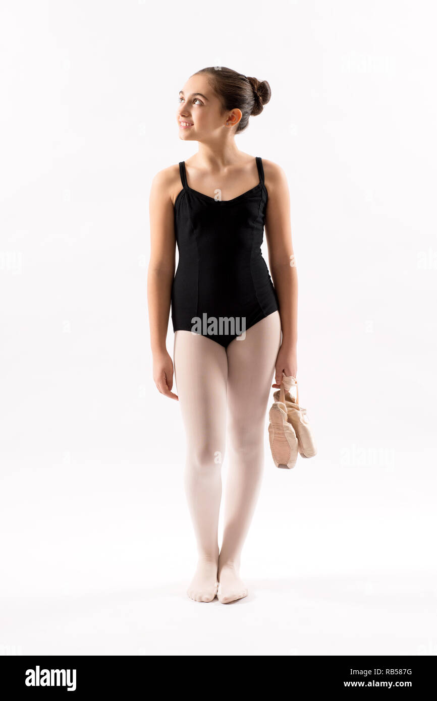 Felice rilassata attraente giovane ballerina in un body in piedi tenendo le sue scarpe cercando da parte con un sorriso più bianco Foto Stock