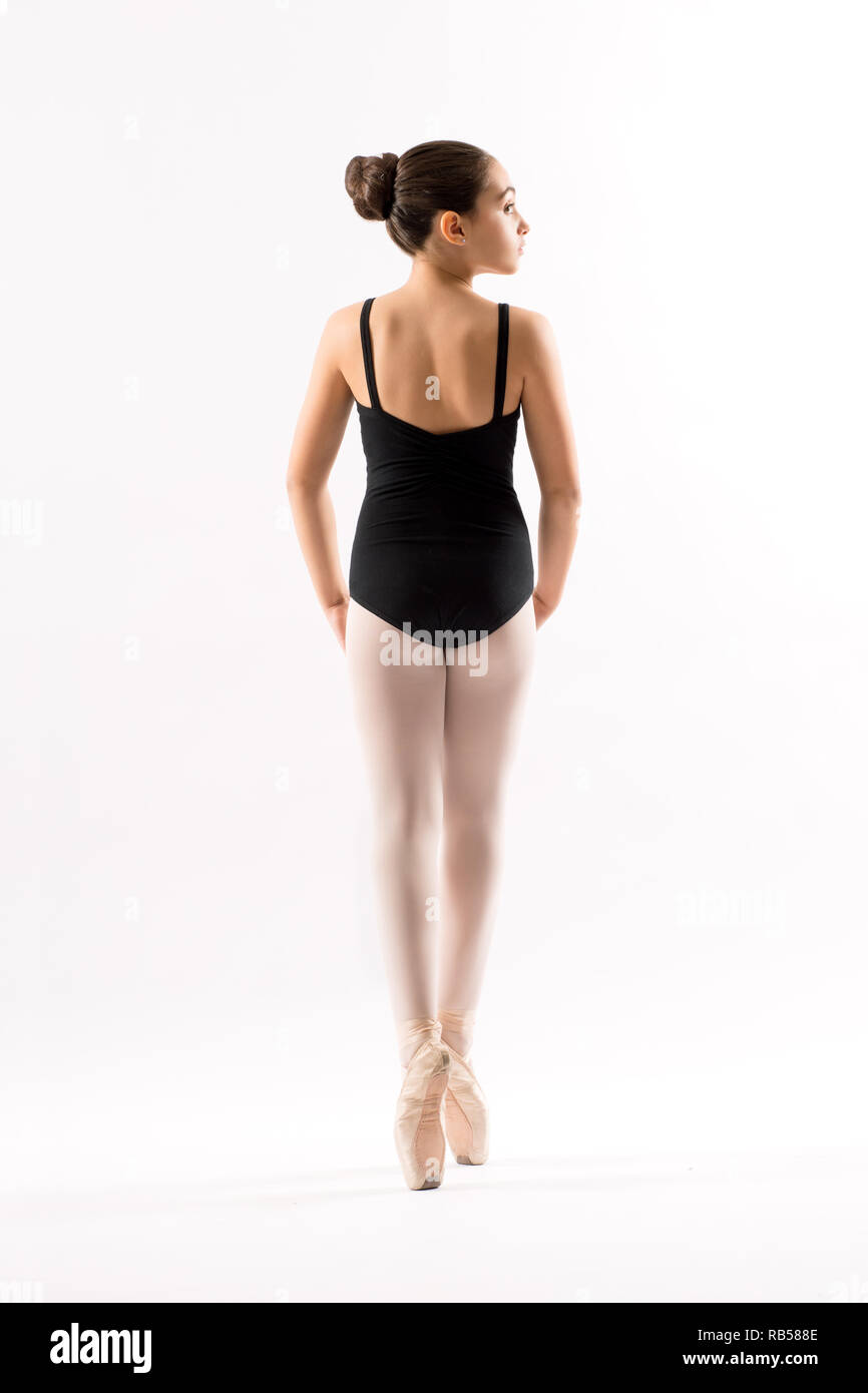 Vista posteriore di una giovane ballerina in un nero leotard posa sul pointe equilibratura su le punte delle sue dita isolato su bianco Foto Stock