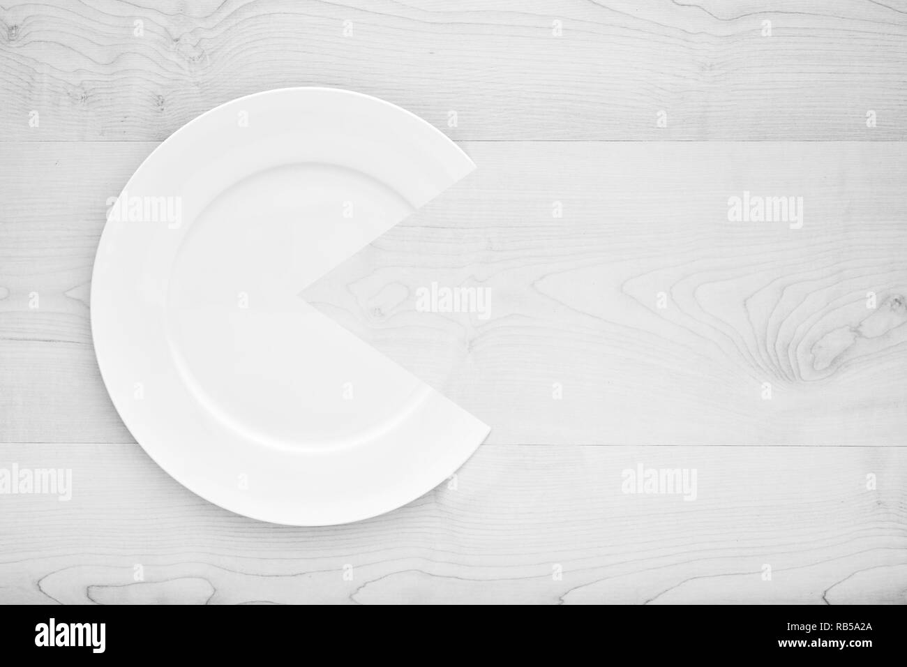 Bianco vuoto piatto rotondo piastra in forma emoji con una bocca aperta su bianco tavolo in legno. Concetto di mangiare e la dieta la violazione. Foto Stock
