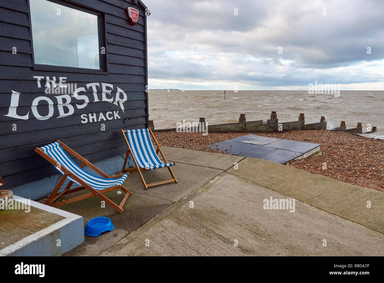 Sedie a sdraio fuori il Lobster Shack, l'East Quay, whitstable kent, in una fredda e blustery giorno di dicembre. Foto Stock