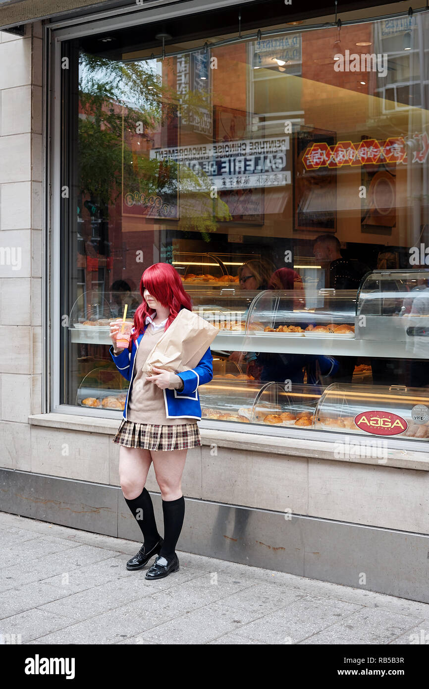 Giovani asiatici teenage schoolgirl indossano uniformi scolastiche detiene un smoothie in mano e si trova di fronte alla vetrina di un negozio Foto Stock