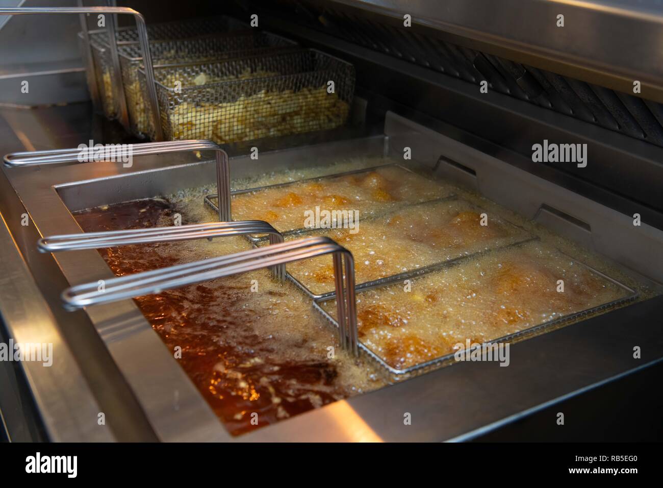 Potato Chips pronto a cuocere in una friggitrice in un chip shop nel Regno Unito. Foto Stock