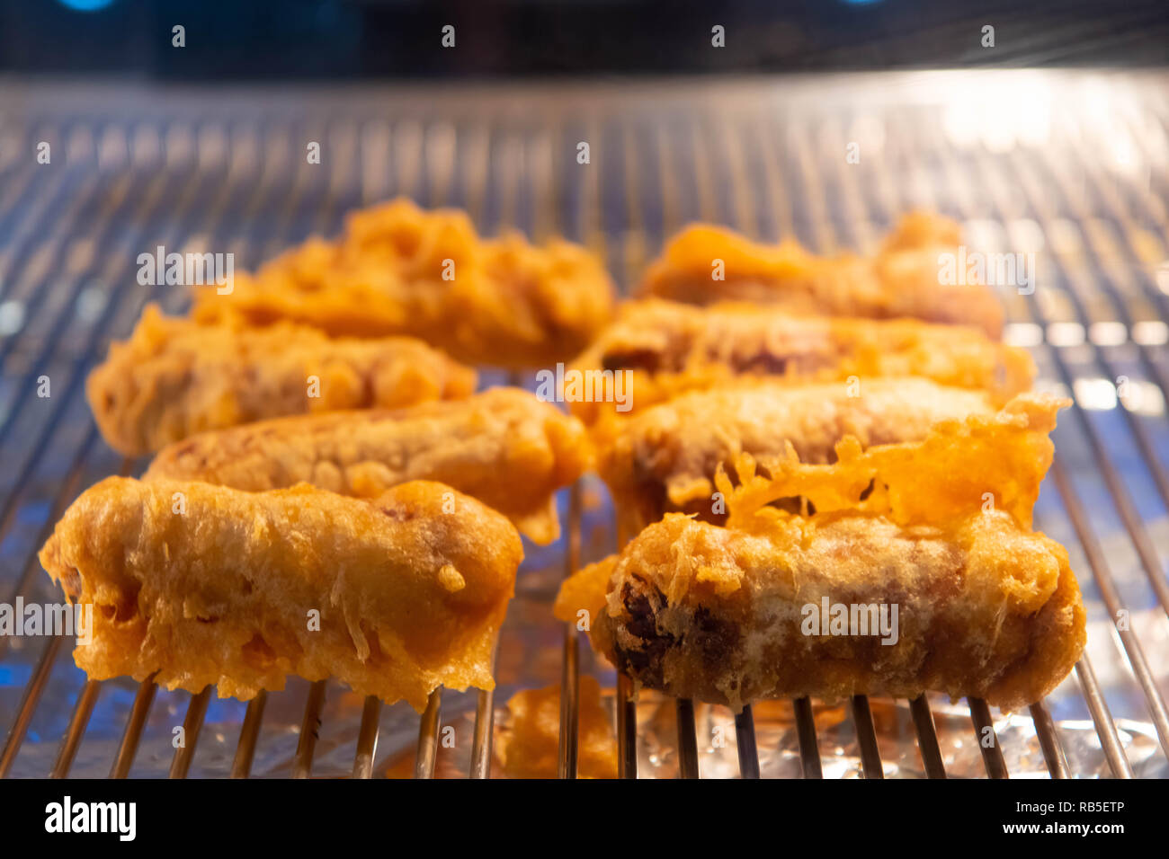 Salsicce in pastella sotto una lampada di calore in un chip shop nel Regno Unito. Foto Stock