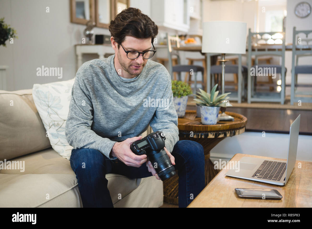 Uomo che utilizza una fotocamera digitale nel soggiorno Foto Stock