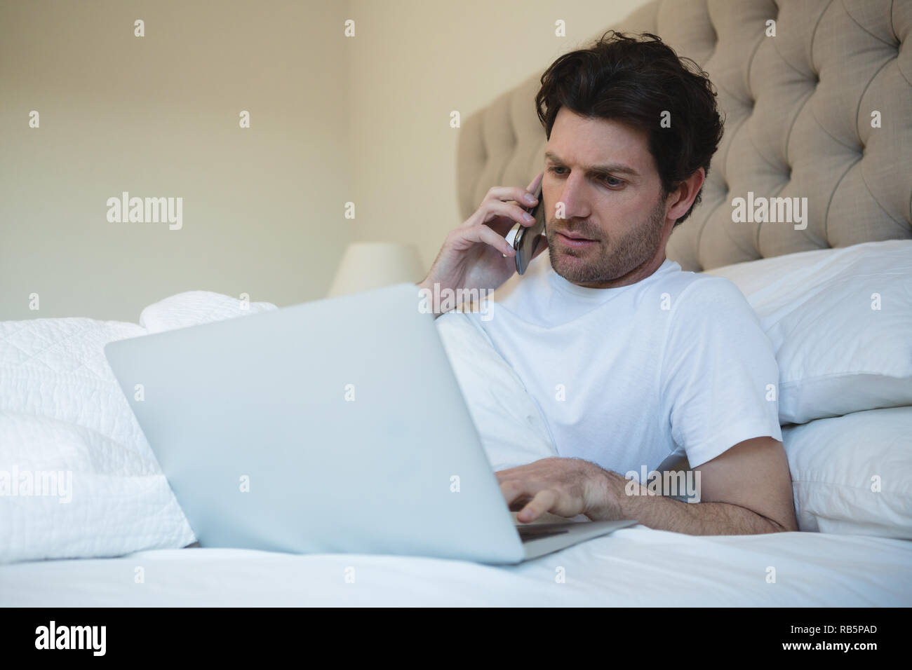 Uomo con notebook mentre si parla al telefono cellulare Foto Stock