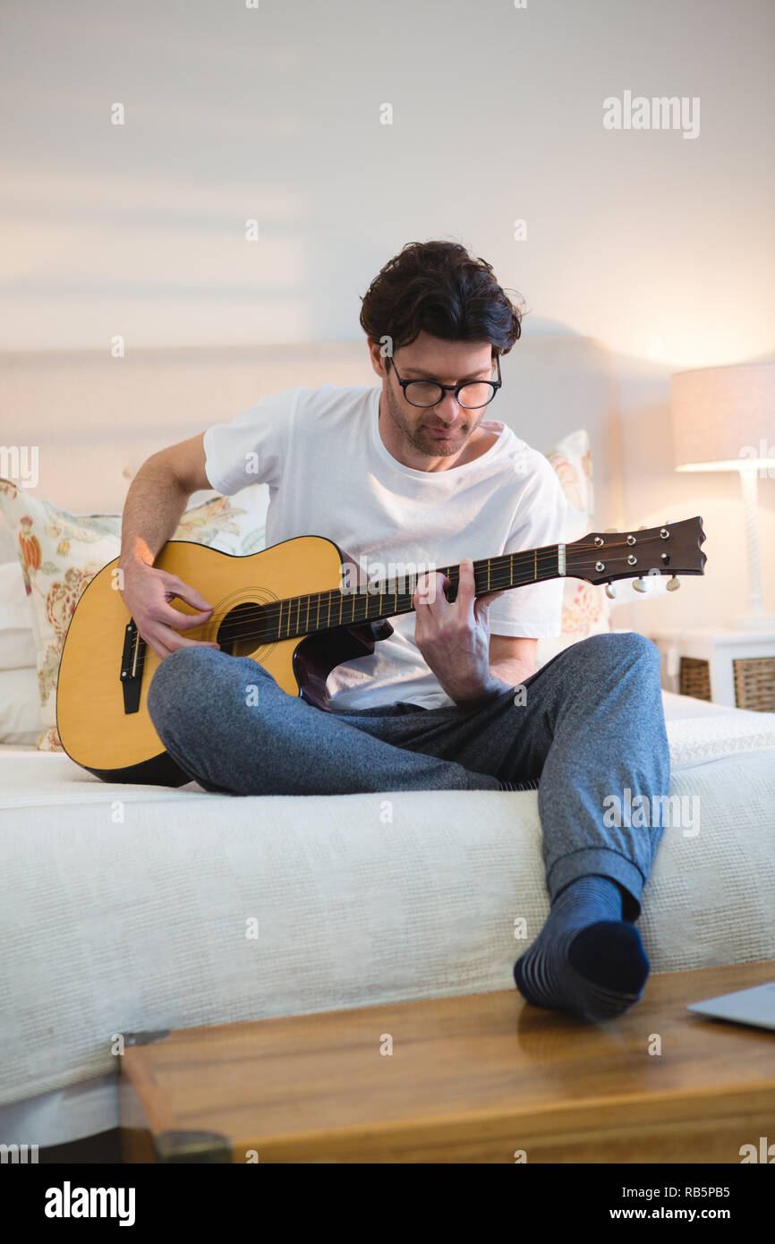 Uomo a suonare la chitarra in camera da letto Foto Stock