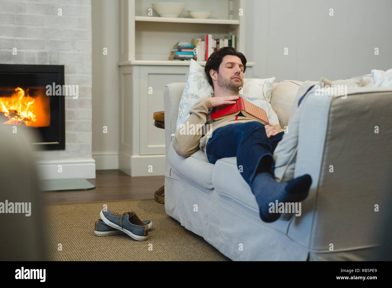 Uomo che dorme sul divano nel soggiorno Foto Stock
