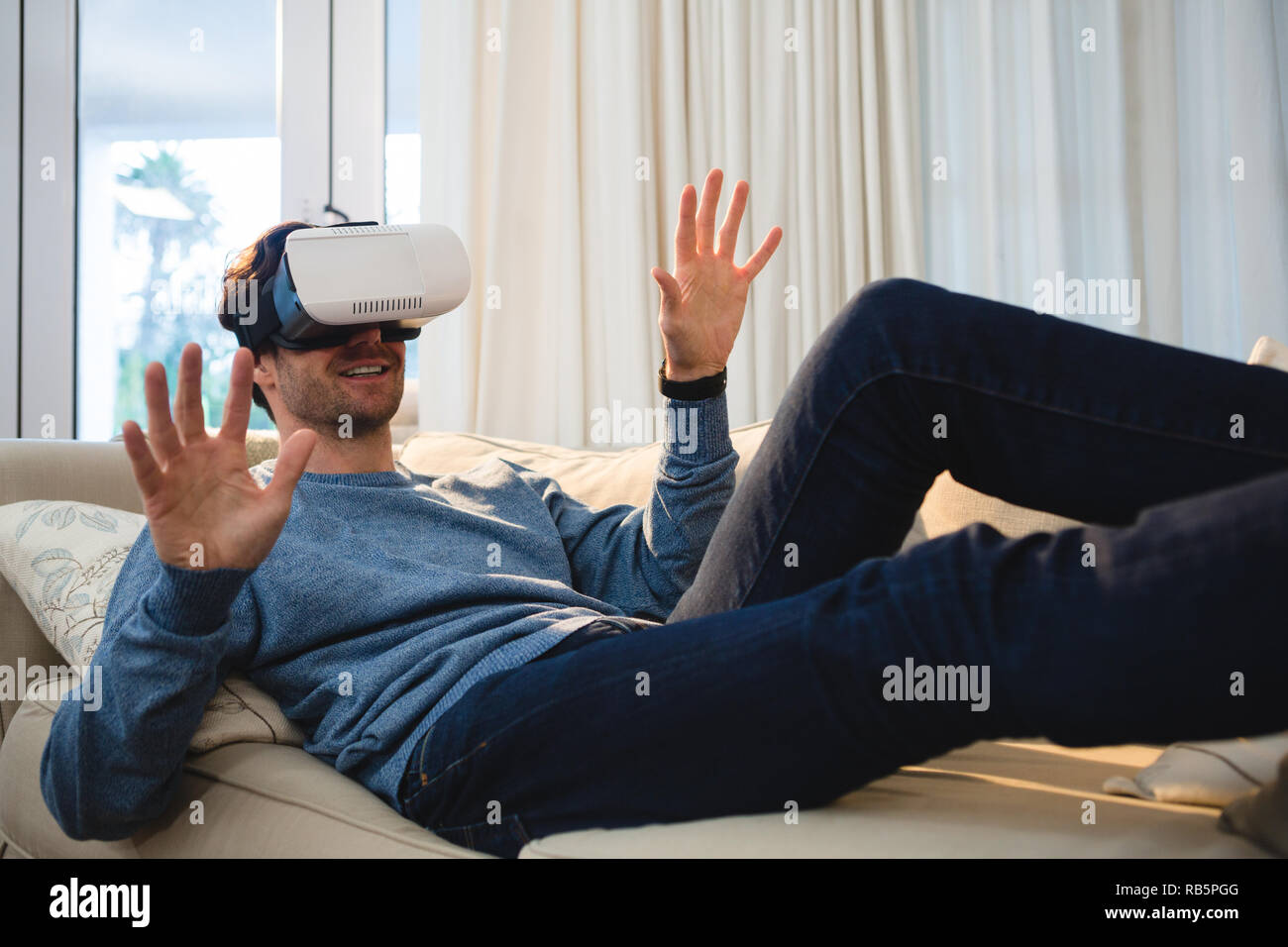 Uomo con la realtà virtuale auricolare in salotto Foto Stock