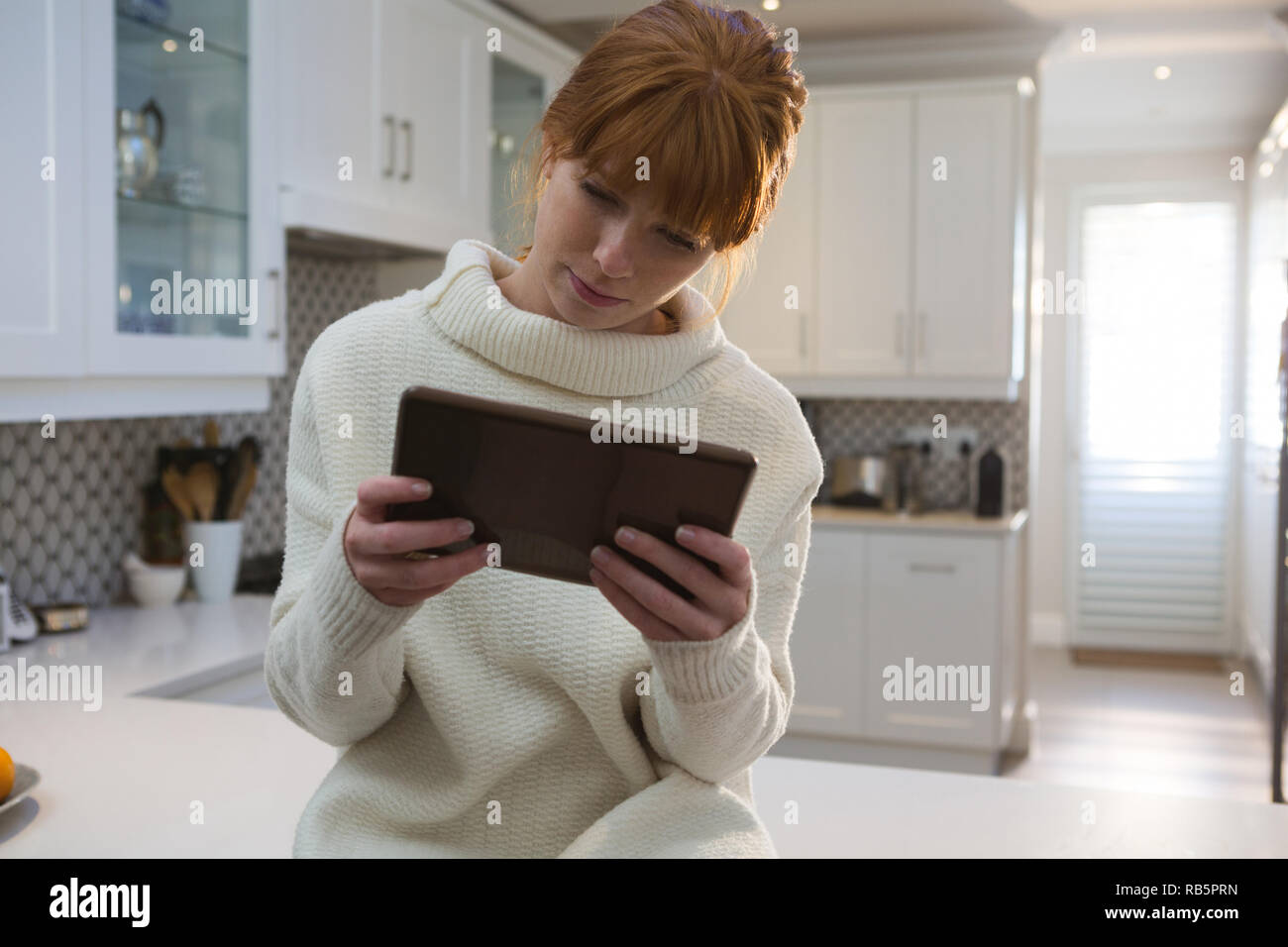 Donna con tavoletta digitale in cucina Foto Stock