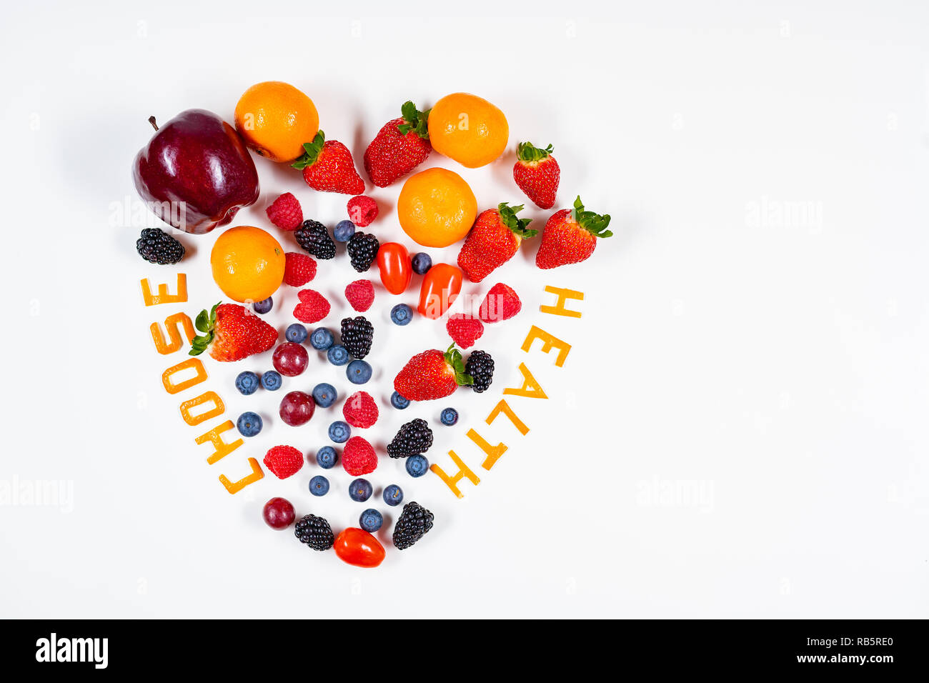 A forma di cuore la disposizione di frutta con scegliere messaggi sulla salute in essa fatta di bucce di mandarino in un pulito lo sfondo bianco con copia spazio. Foto Stock