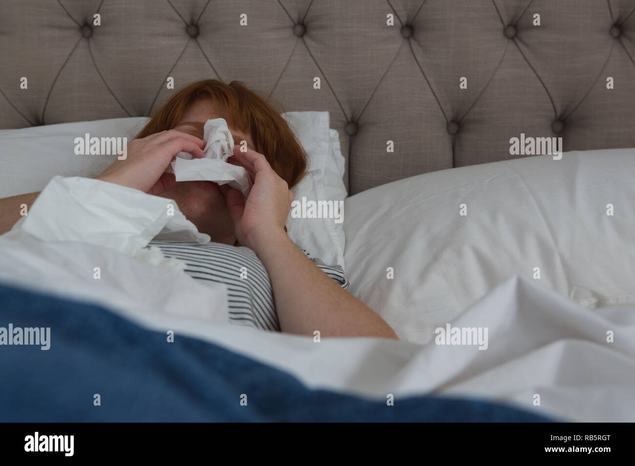 Donna starnuti in carta tissue in camera da letto Foto Stock