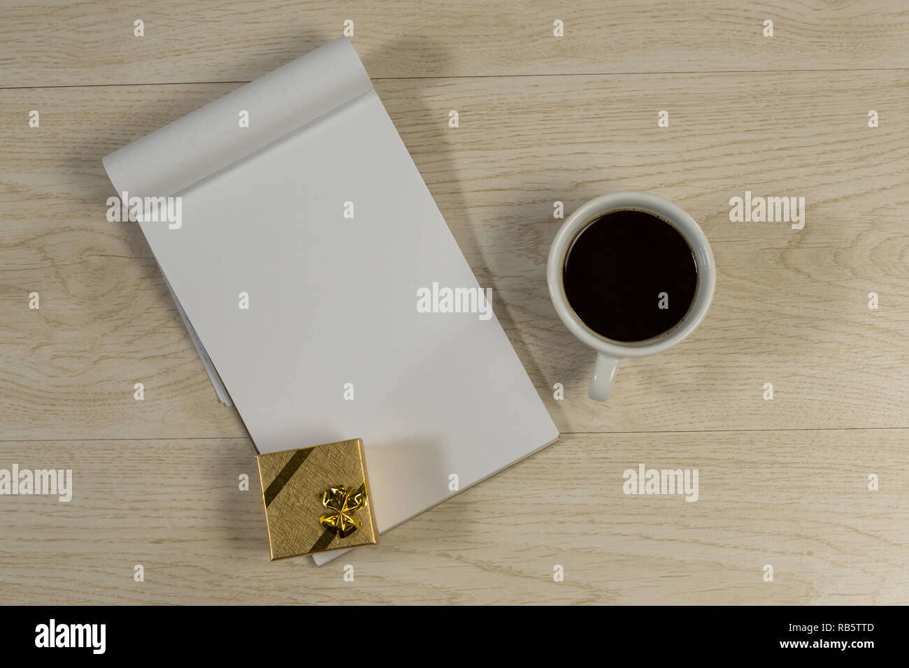 Confezione regalo, notepad e caffè nero sul tavolo di legno Foto Stock