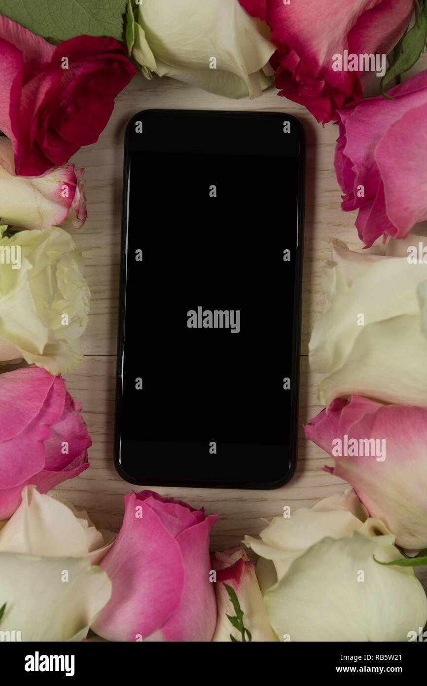 Telefono cellulare circondato con fiore rosa Foto Stock