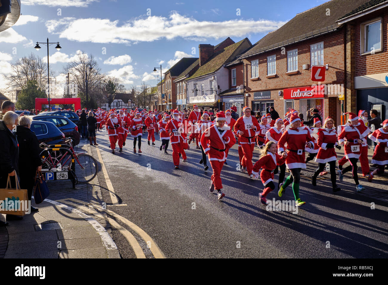 La gente vestita come Babbo Natale che hanno appena cominciato a prendere parte al grande Thatcham Santa Fun Run in Thatcham high street mentre la gente guarda su Foto Stock