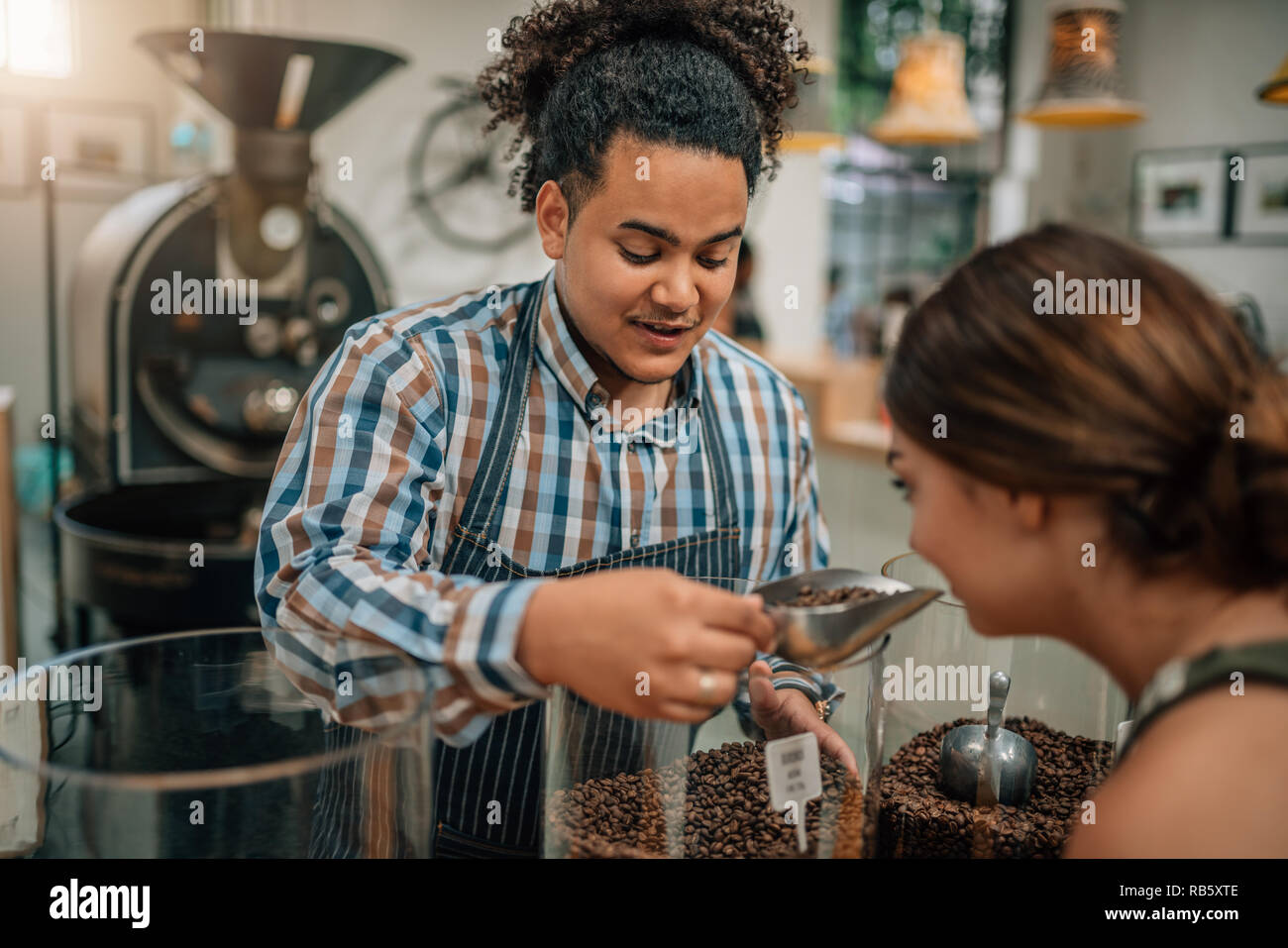La tostatura del fagiolo conoscitore permettendo al cliente di annusare l'aroma del caffè in grani Foto Stock